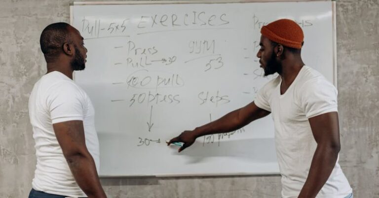 Sports Planning - Two Men Looking At A Workout Schedule On A Whiteboard