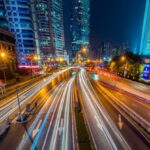 Smart Cities - Timelapse Photography of Vehicle on Concrete Road Near in High Rise Building during Nighttime