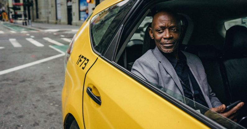 Transport Use - Happy confident mature African American male looking away and expecting important message on mobile phone while sitting in yellow automobile