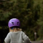 Transport Safety - Anonymous kid in helmet riding run bike on pavement in countryside