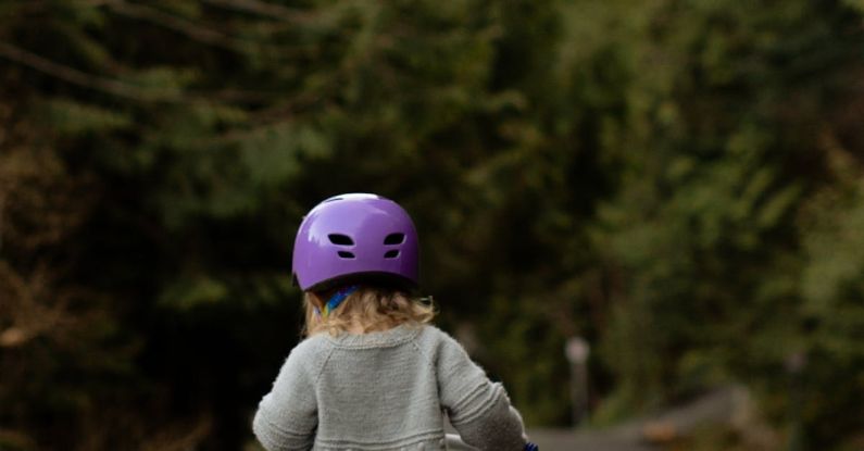 Transport Safety - Anonymous kid in helmet riding run bike on pavement in countryside