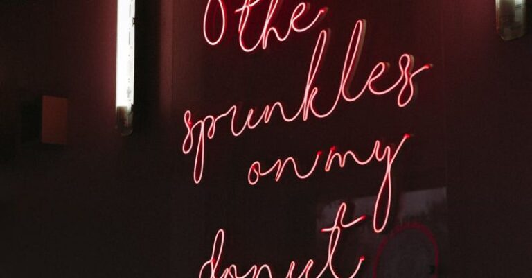 Public Art - Red neon signboard with inscription hanging on wall in dark public place at night