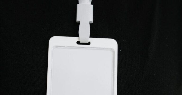 Event Security - Plastic name tag with white ribbon and blank paper hanging on black background