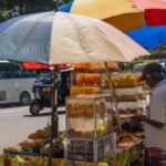 Food Tourism - A man selling fruit on a street corner